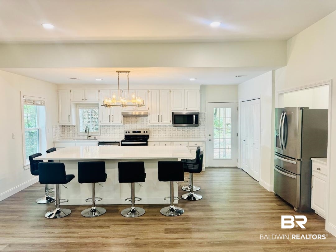 2663 Demetropolis Road Mobile, AL 36693 - Photo 10 of 26 Kitchen featuring stainless steel appliances, light countertops, white cabinets, tasteful backsplash, and light wood-style floors
