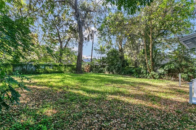 a house that is sitting in the grass with large trees