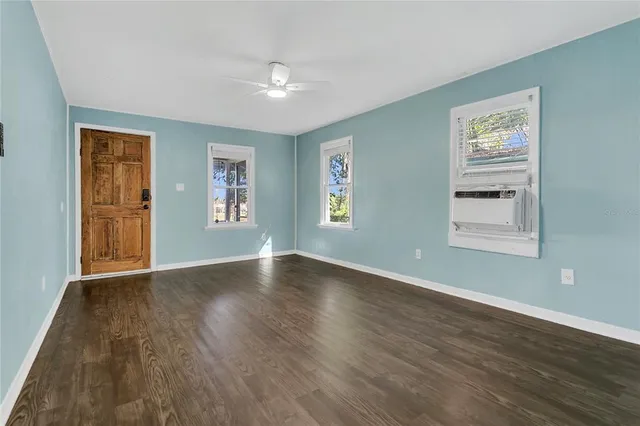 a view of an empty room with wooden floor and a window