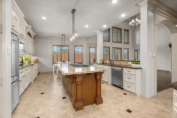 a large kitchen with granite countertop a stove oven and white cabinets