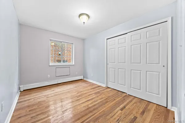 an empty room with wooden floor closet and windows
