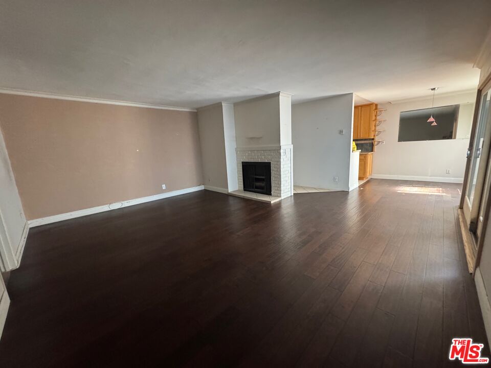 12030 Rochester Avenue, Unit 207 Los Angeles, CA 90025 - Photo 4 of 12 an empty room with wooden floor and fireplace