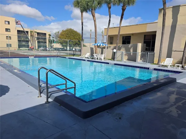 a view of a patio with table and chairs under an umbrella with a garden