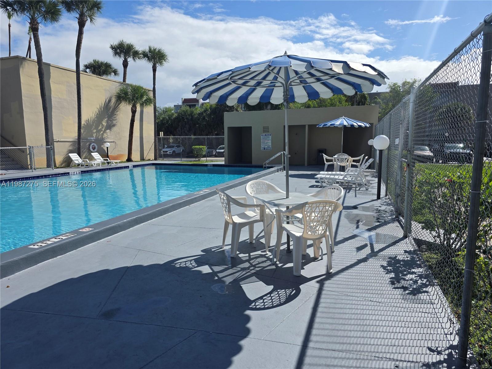 8615 Northwest 8th Street, Unit 319 Miami, FL 33126 - Photo 13 of 19 a view of a patio with table and chairs under an umbrella with a garden