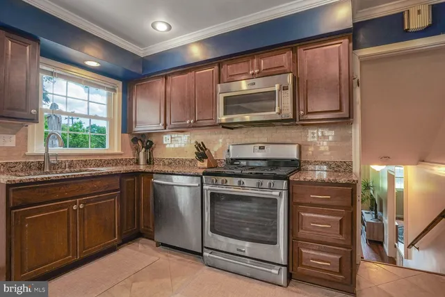 a kitchen with stainless steel appliances granite countertop a stove top oven a sink and a microwave