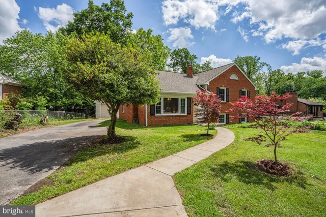 a front view of a house with a yard and tree