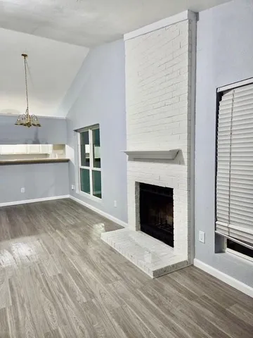 a view of an empty room with wooden floor fireplace and a window