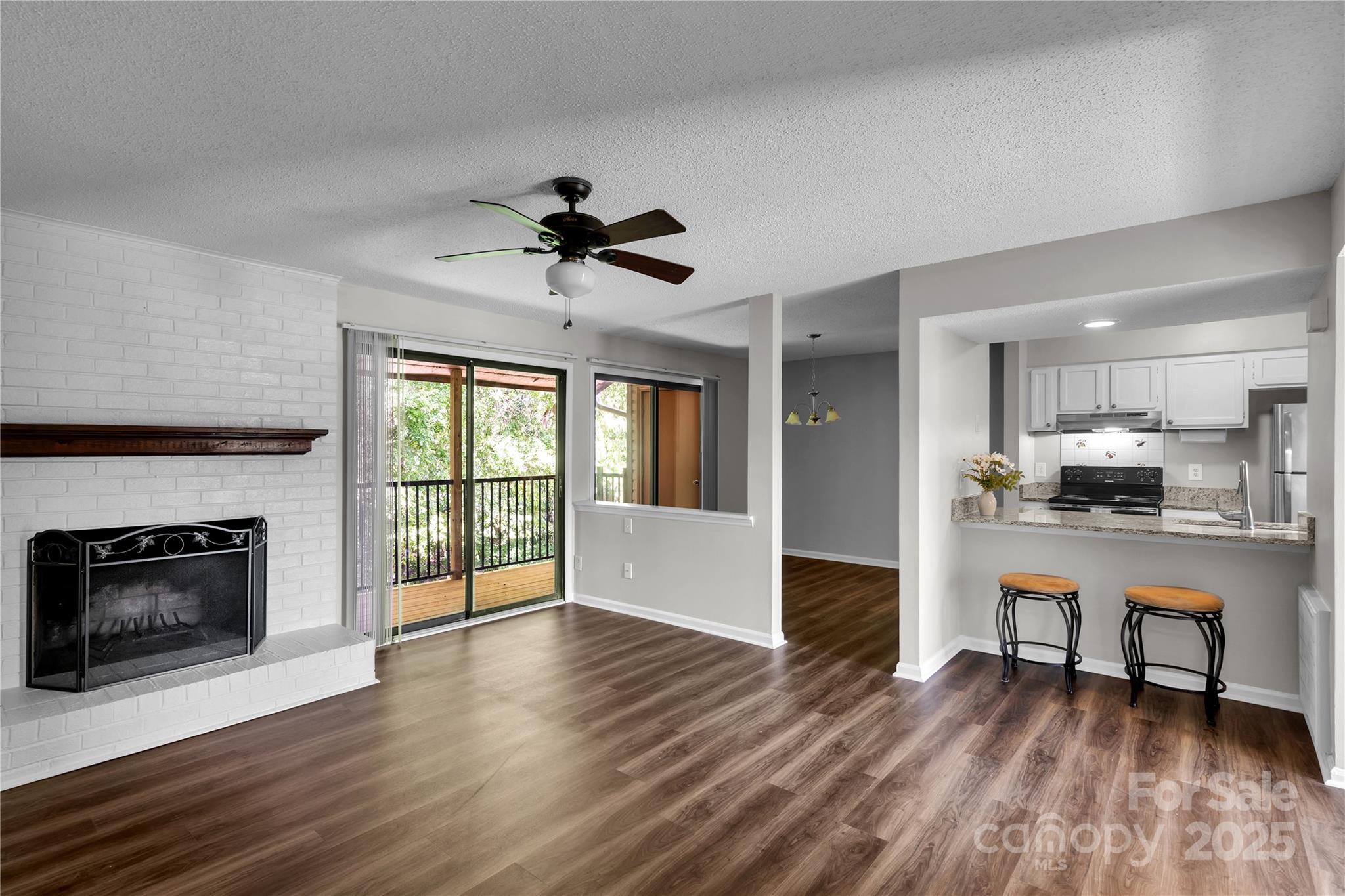 a view of an empty room with wooden floor and a fireplace