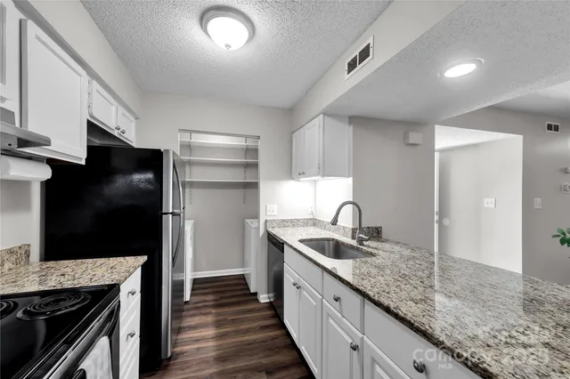 a kitchen with granite countertop stainless steel appliances a sink and a refrigerator