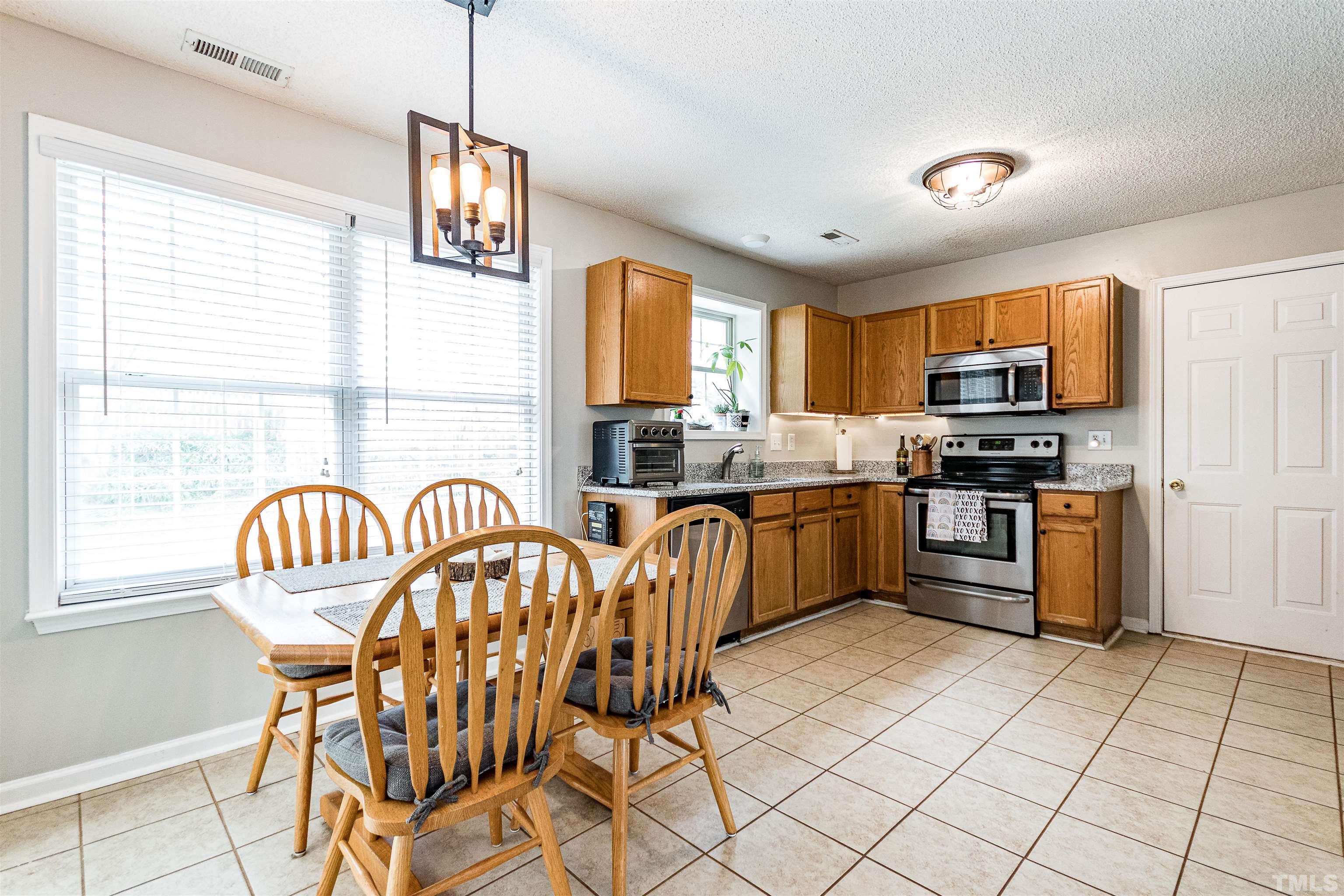 107 Ridge Lake Drive Apex, NC 27539 - Photo 7 of 27 a kitchen with granite countertop a stove a sink a dining table and chairs