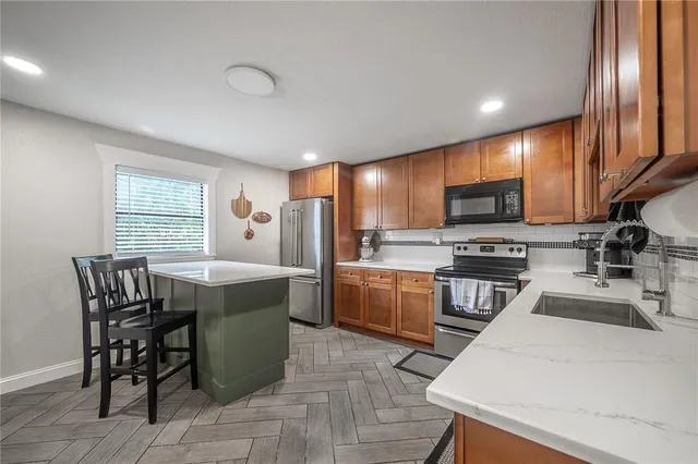 a kitchen with stainless steel appliances kitchen island granite countertop a sink table and chairs