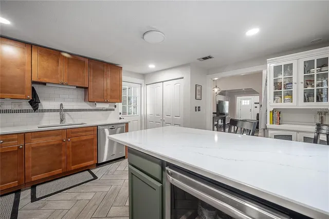 a kitchen with stainless steel appliances a sink dishwasher stove refrigerator and cabinets