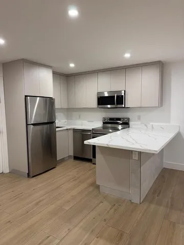 a kitchen with stainless steel appliances granite countertop a refrigerator a stove a sink and a microwave