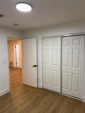 a view of an empty room and wooden floor and closet area