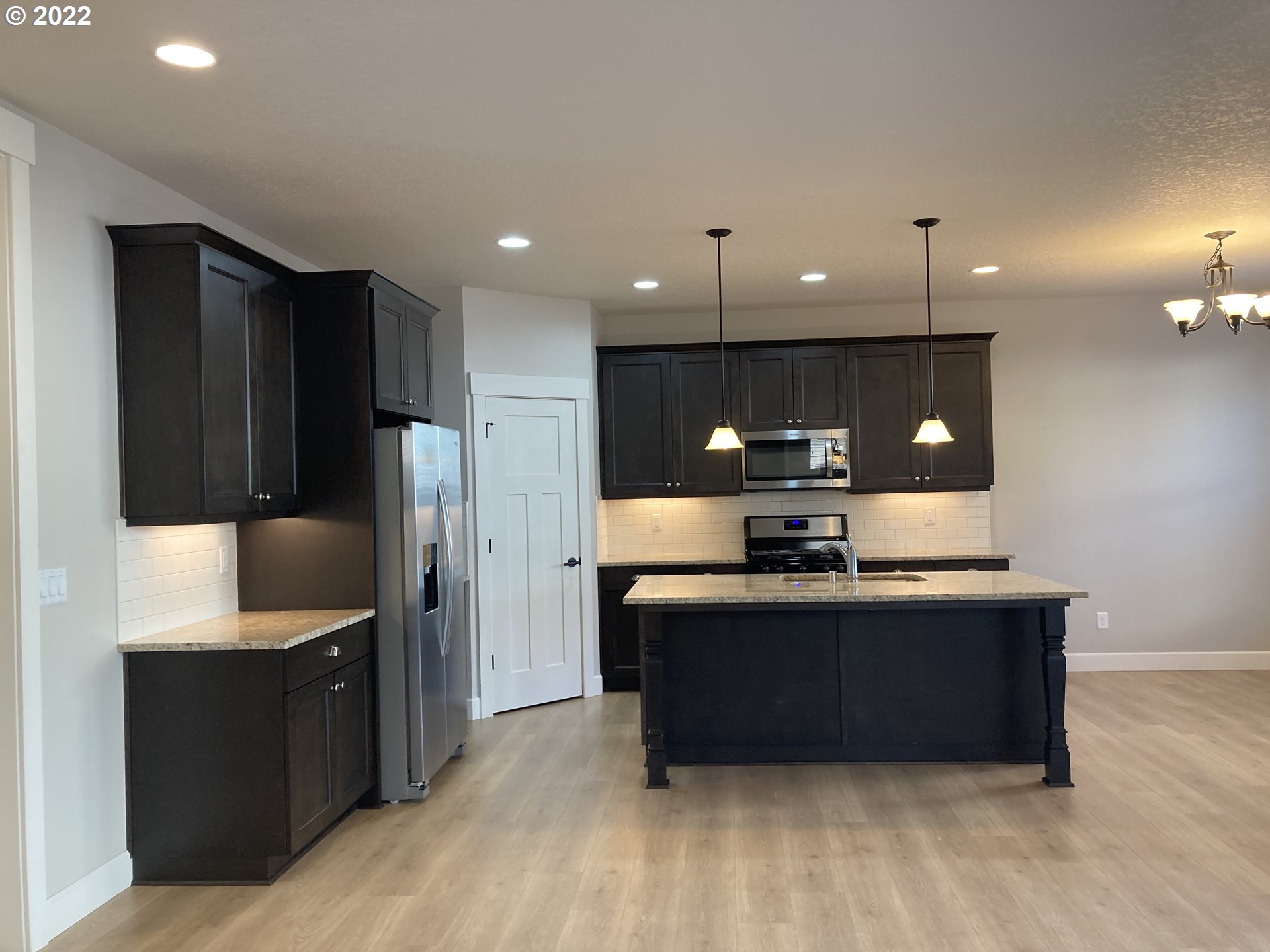 1204 South Quail Run Place Ridgefield, WA 98642 - Photo 8 of 25 a kitchen with kitchen island stainless steel appliances a sink cabinets and wooden floor