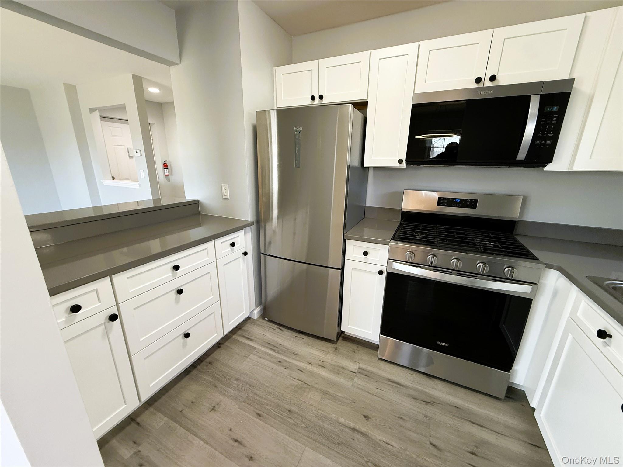 a kitchen with granite countertop white cabinets and stainless steel appliances