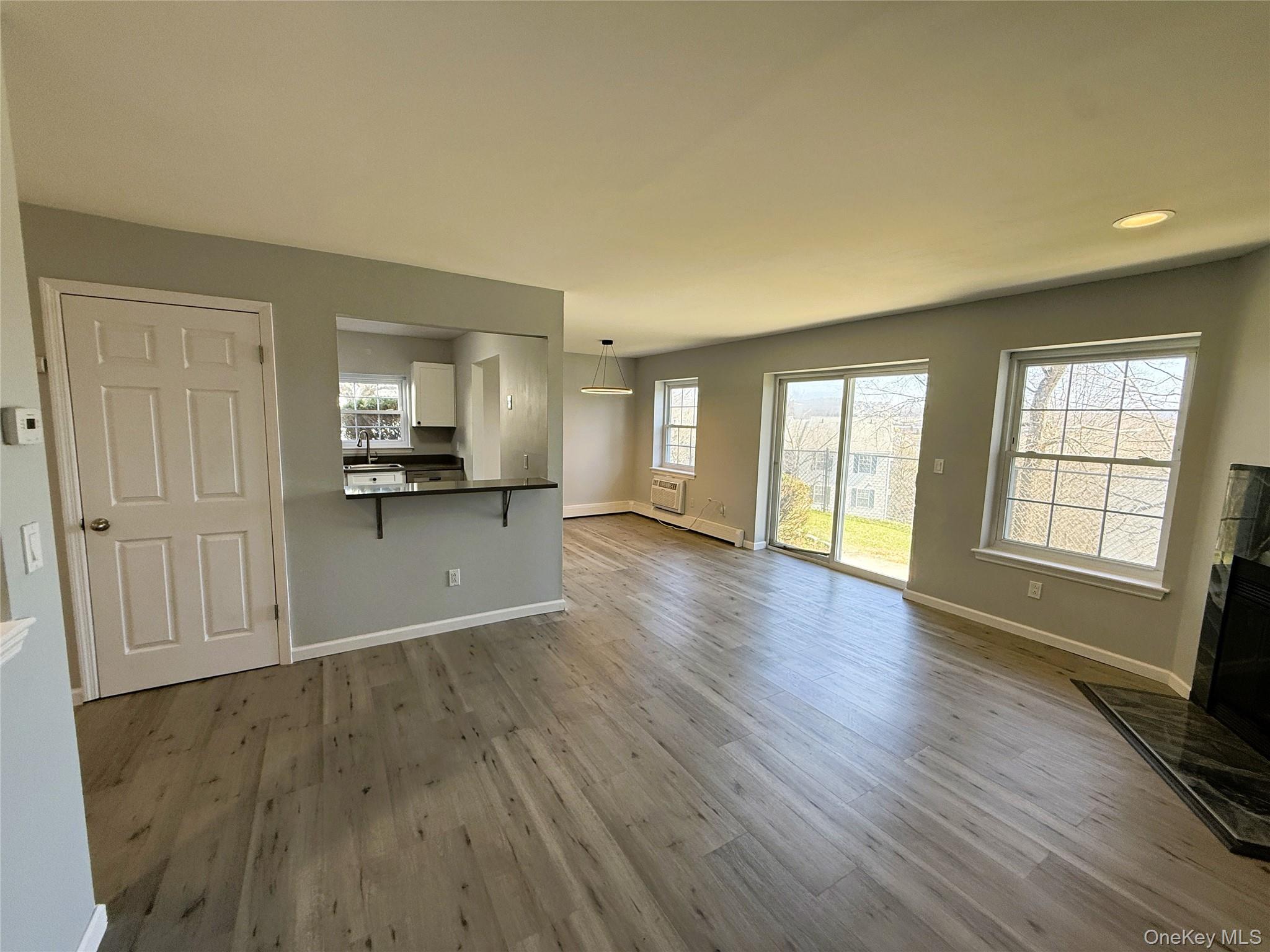 25 Lexington Hills Road, Unit 8 Harriman, NY 10926 - Photo 6 of 24 a view of a kitchen and an empty room with wooden floor and a window