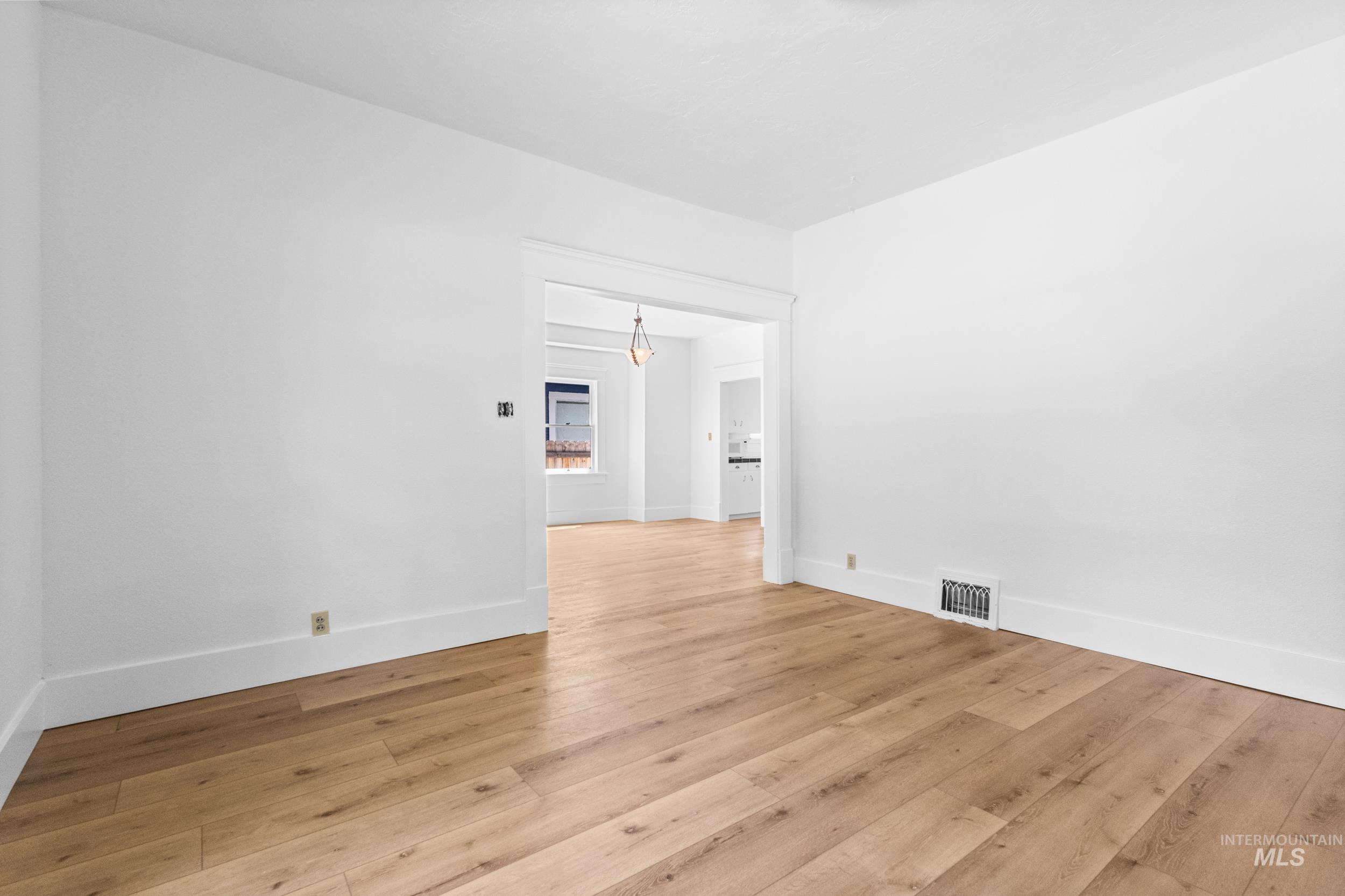 2119 West Brumback Street Boise, ID 83702 - Photo 11 of 30 Spacious interior featuring wood-finish flooring, white walls, white baseboards, and a wide doorway with white trim