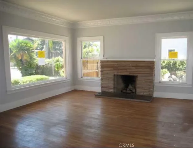 an empty room with wooden floor fireplace and windows