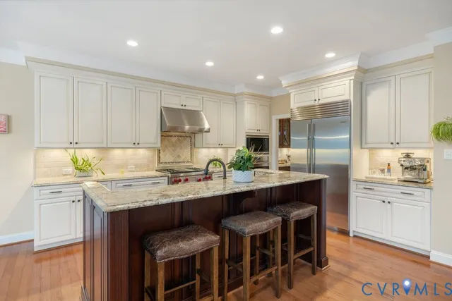 a kitchen with stainless steel appliances granite countertop a table chairs sink refrigerator and cabinets