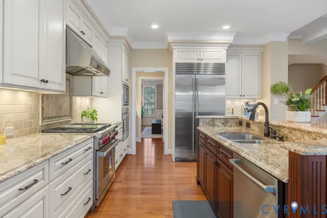 a kitchen with stainless steel appliances granite countertop a sink a stove and a refrigerator