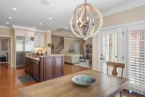 a kitchen with stainless steel appliances granite countertop a stove top oven a sink dishwasher a dining table and chairs with wooden floor