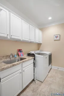 a utility room with sink dryer and cabinets