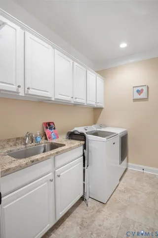a utility room with sink dryer and cabinets