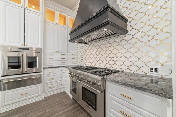 a kitchen with granite countertop white cabinets stainless steel appliances and wooden floor