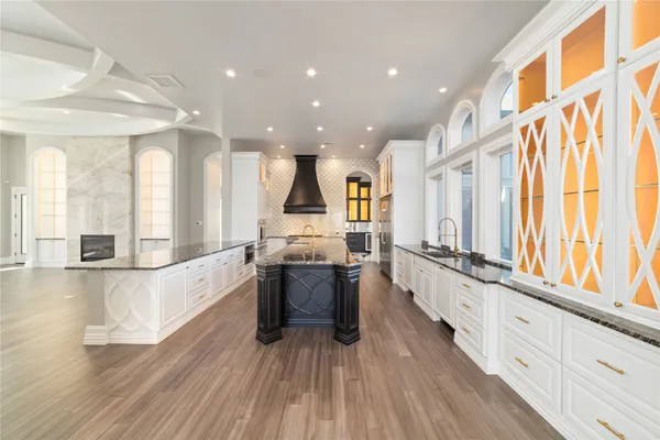 a large kitchen with stainless steel appliances a large counter top a stove and a wooden floors