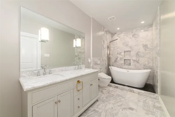 a bathroom with a bathtub a sink and a large mirror