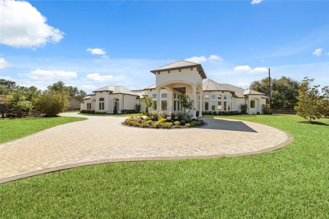 a view of a white house with a big yard and potted plants