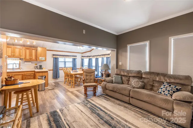 a kitchen with granite countertop lots of white cabinets a sink dishwasher a dining table and chairs with wooden floor