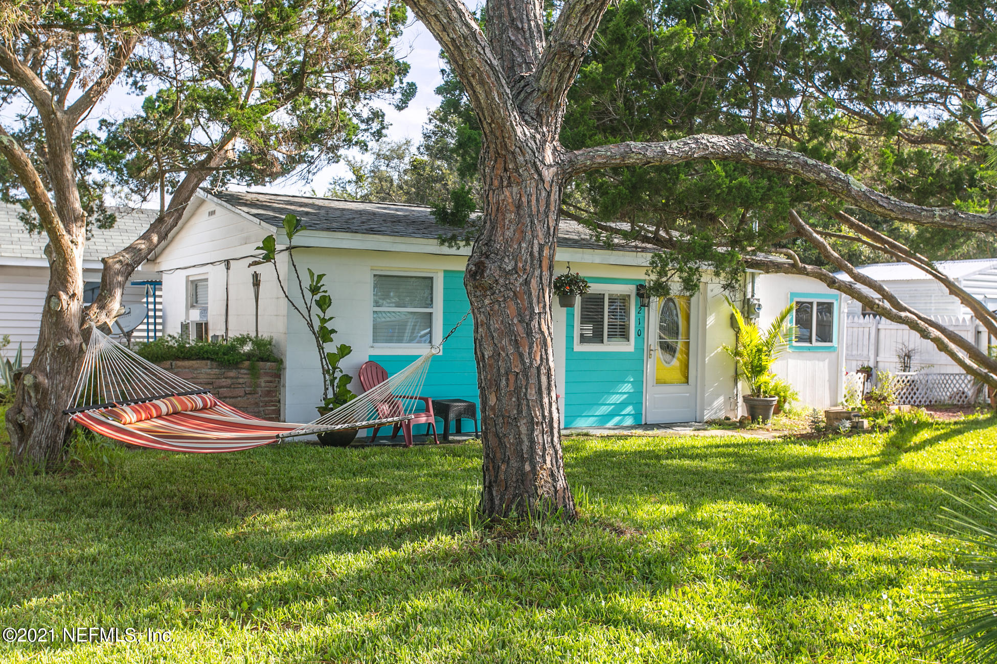 210 Palmetto Road St. Augustine, FL 32080 - Photo 11 of 16 a view of a white house with a big yard and potted plants and large trees