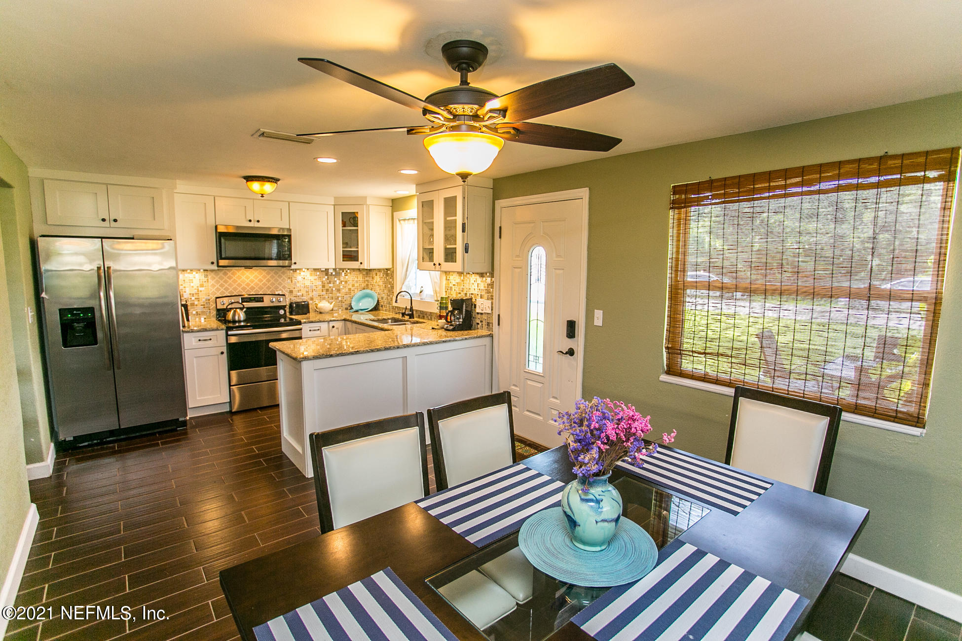 210 Palmetto Road St. Augustine, FL 32080 - Photo 2 of 16 a kitchen with stainless steel appliances kitchen island granite countertop a refrigerator a sink dishwasher a dining table and chairs with wooden floor