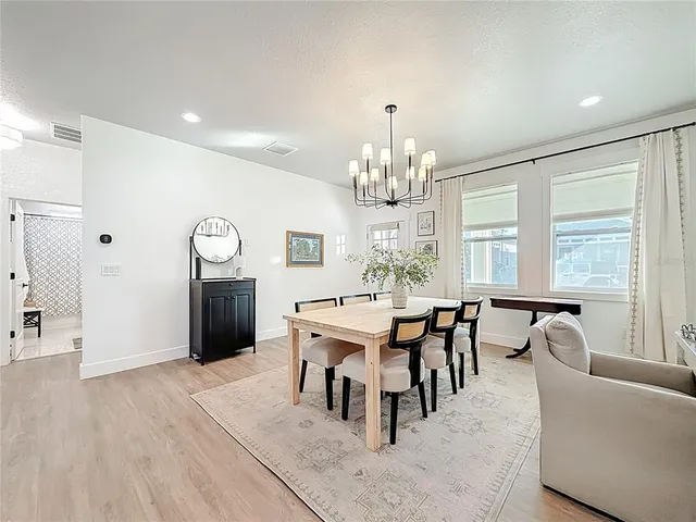 a kitchen with stainless steel appliances kitchen island granite countertop a refrigerator a stove a sink dishwasher and a dining table with wooden floor