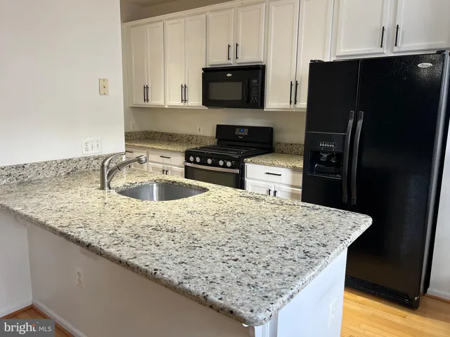 a kitchen with granite countertop a refrigerator a stove and a sink