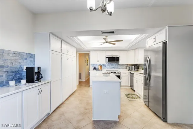 a large white kitchen with cabinets a sink and stainless steel appliances