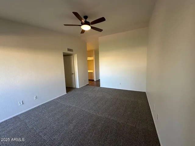 an empty room with a chandelier fan and a bathroom