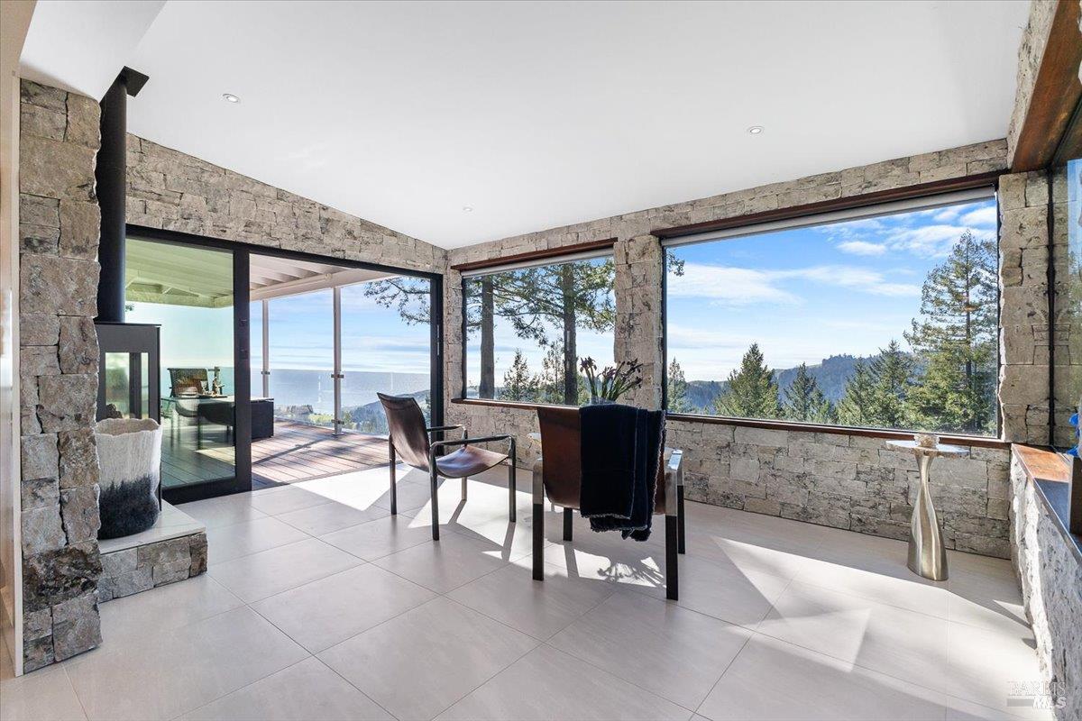 3100 Muniz Ranch Road Jenner, CA 95450 - Photo 32 of 83 Fully enclosed, stone-clad sunroom with a fireplace opens seamlessly to an expansive deck, creating an ideal indoor-outdoor living experience.