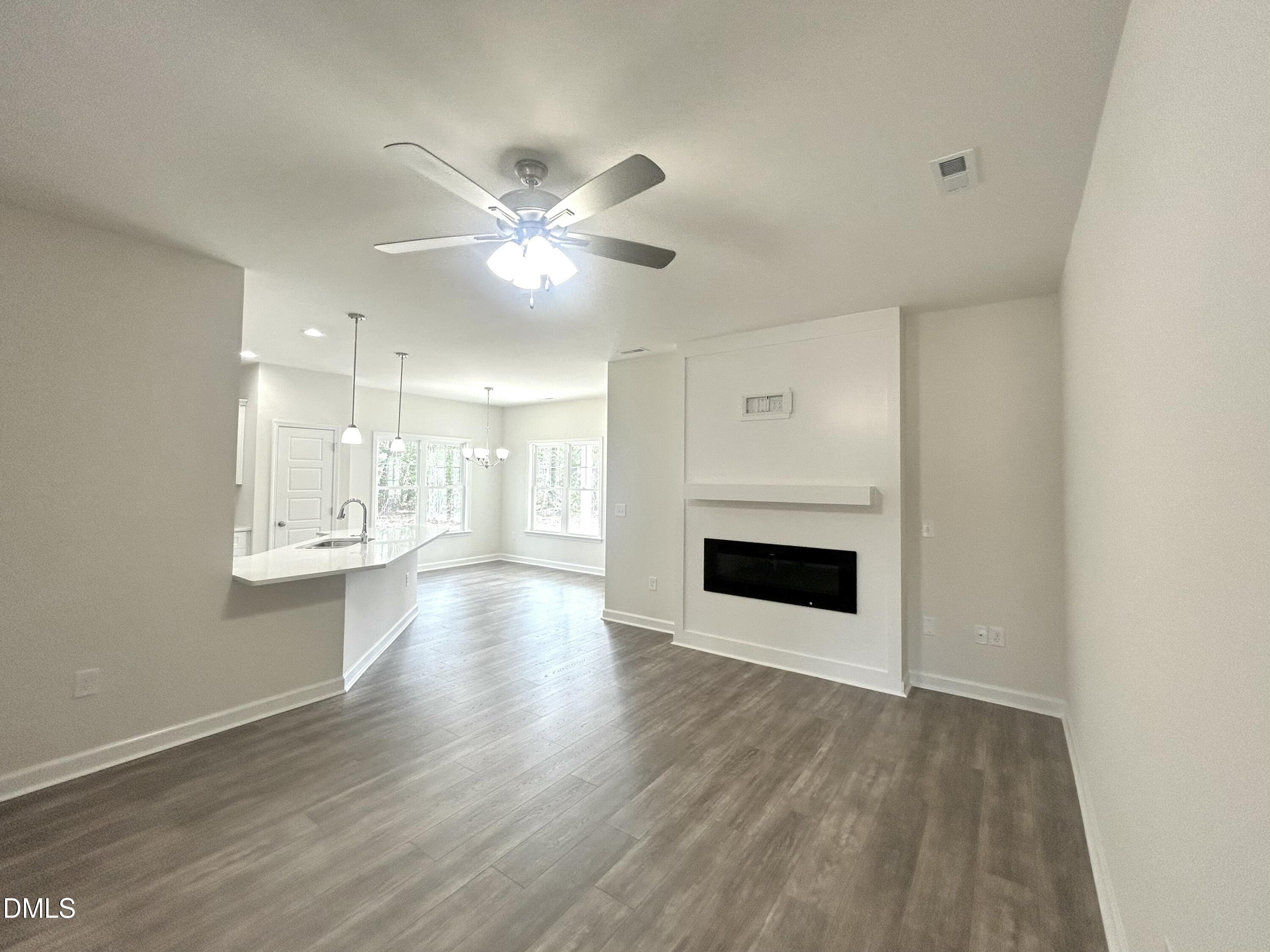 1725 Cardinal Drive Deep Run, NC 28525 - Photo 3 of 21 an empty room with wooden floor fireplace and windows