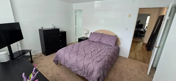 a bedroom with a bed and a flat tv screen on the dresser