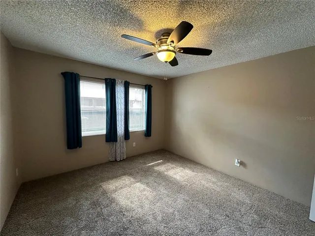 an empty room with windows and fan