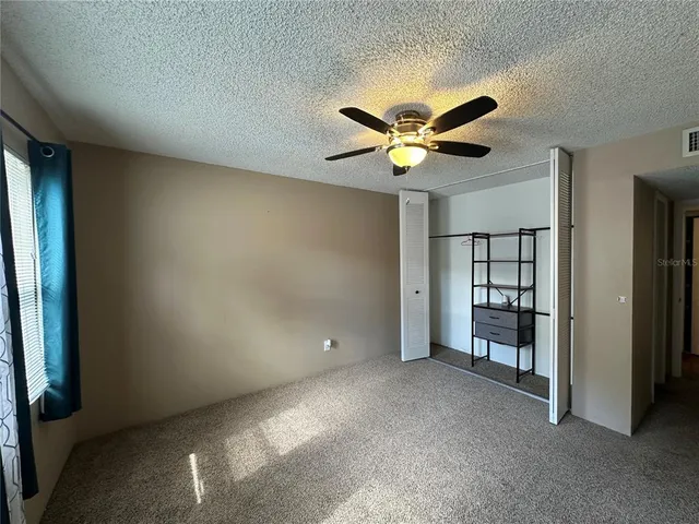 an empty room with windows and fan