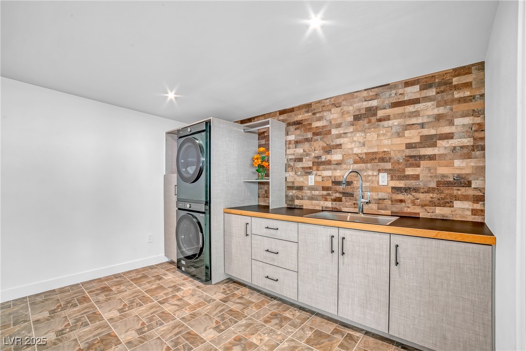 1318 Denver Street Boulder City, NV 89005 - Photo 23 of 32 Washroom with stacked washing machine and dryer, tile floors, brick finished wall and cabinet space