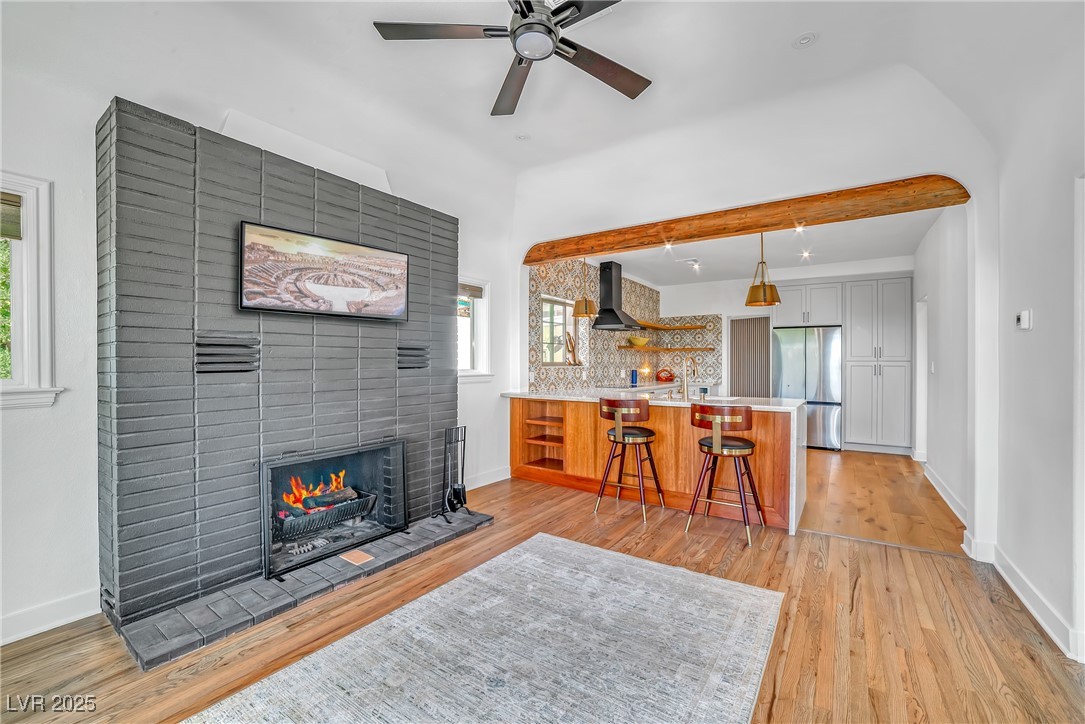 1318 Denver Street Boulder City, NV 89005 - Photo 8 of 32 Living area featuring a fireplace, light wood finished floors, exposed ceiling wood beam over breakfast bar, and ceiling fan