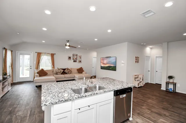a kitchen with granite countertop a sink cabinets and wooden floor