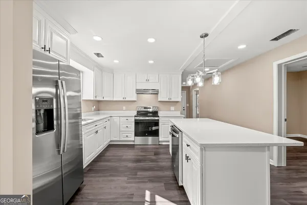 a large kitchen with a center island wooden floor stainless steel appliances and a window
