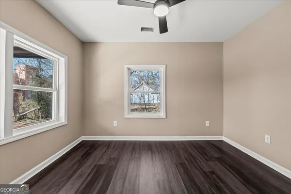 a view of empty room with wooden floor and fan