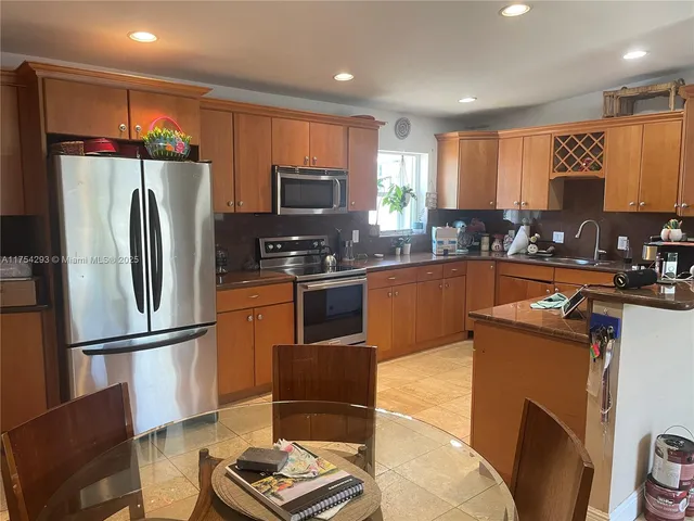 a kitchen with kitchen island a counter top space cabinets stainless steel appliances and a window